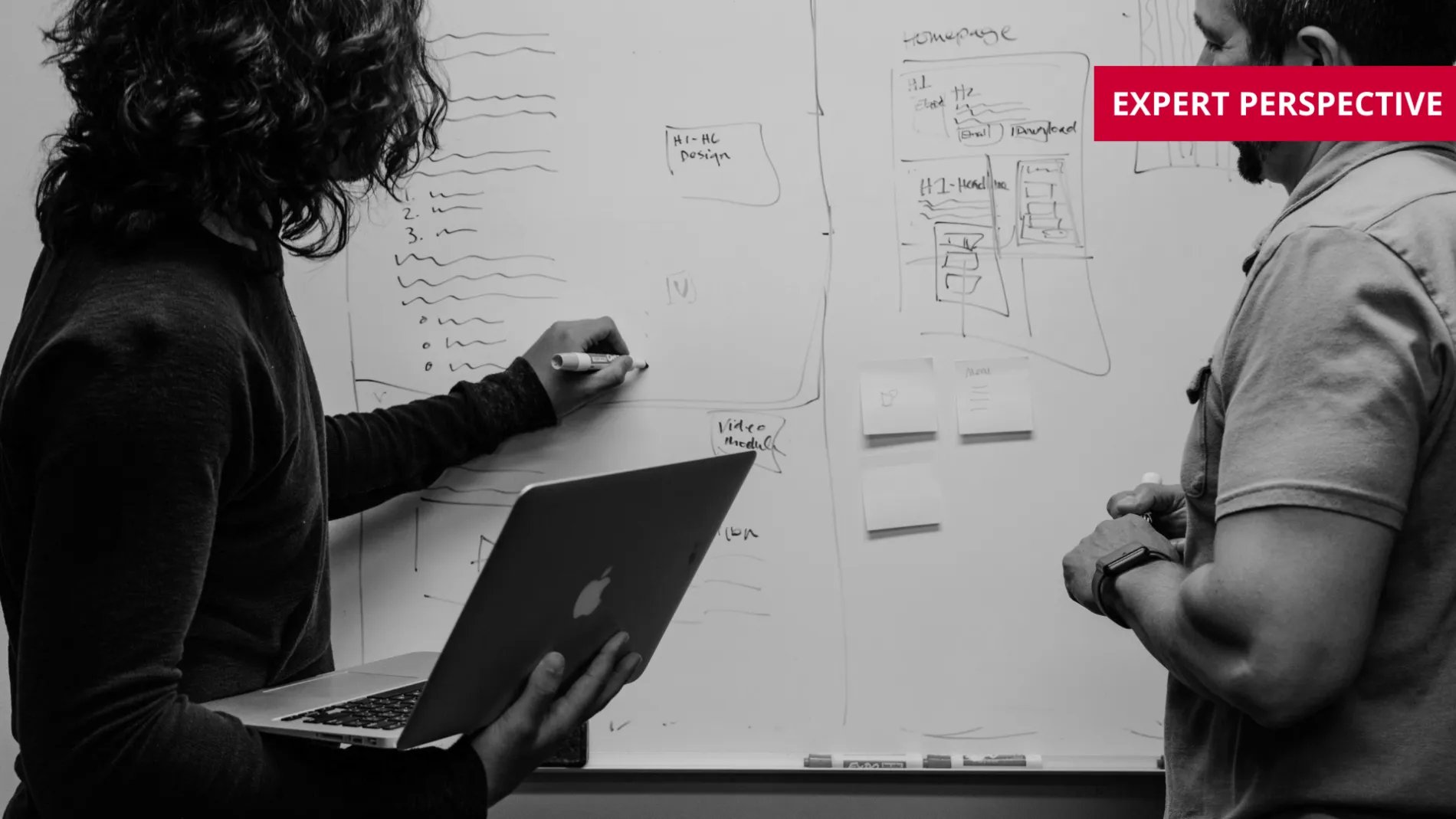 Two people discussing plans at a whiteboard