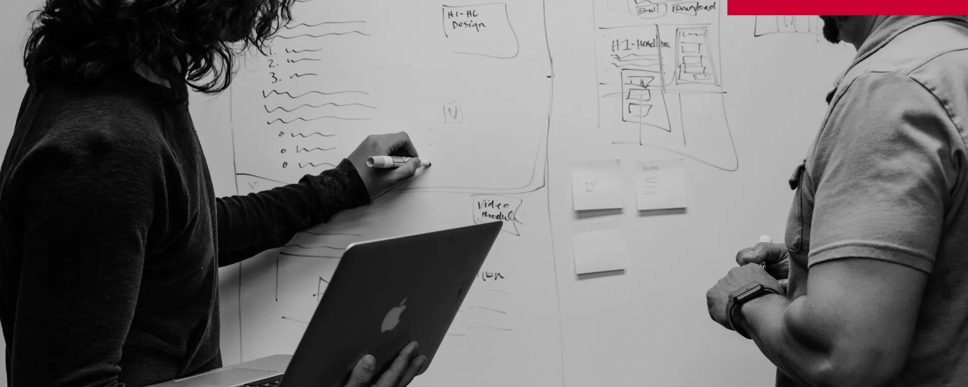 Two people discussing plans at a whiteboard
